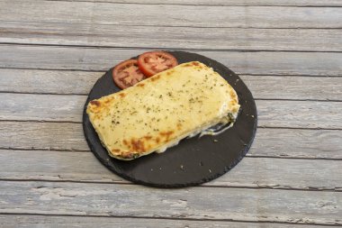 Lazanya porsiyonu ıspanak ve kekik peyniri ile dolu ve yuvarlak bir tabağa monte edilmiş.