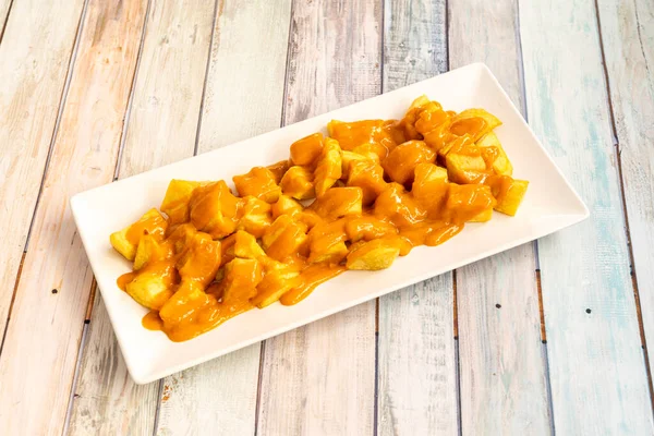 Ration of patatas bravas served as tapas in a restaurant in Madrid on a wooden table