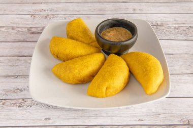 Beyaz bir tabağa batırmak için biraz soslu Kolombiya mısır böreği.