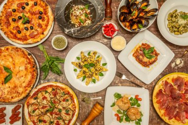 Kahverengi mermer bir masa üzerinde bir sürü fesleğen, pizza, makarna, gnocchi, domates ve sebze içeren tipik İtalyan yemeklerinin en iyi görüntüsü.
