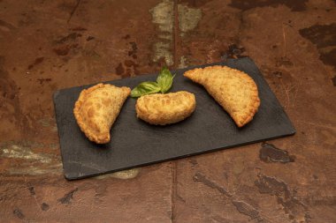 Etle doldurulmuş puf hamur tatlısı ile yapılan çeşitli tatlar ve ekstra bakire zeytinyağında kızartılmış ahşap renkli metal bir masa.