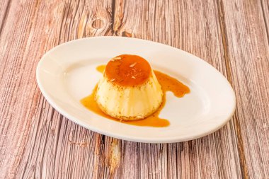 Beyaz tepside şekerli kremalı yumurta ve ahşap masa.