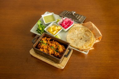 Tahta bir masada birkaç Meksika takosu hazırlamak için gerekli malzemeler.