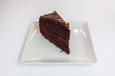 Kare beyaz bir porselen tabakta iki katmanlı browni ve parlak krema.