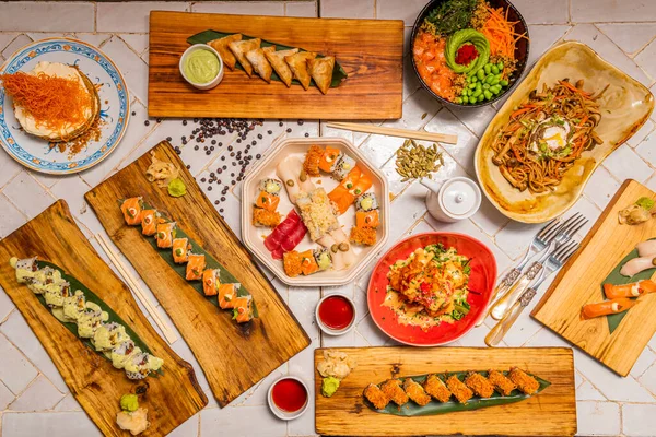 白い食器台にアジア料理と寿司の盛り合わせプレート カリフォルニアロール 握りまぐろ うどん ポークサーモン わかめ — ストック写真