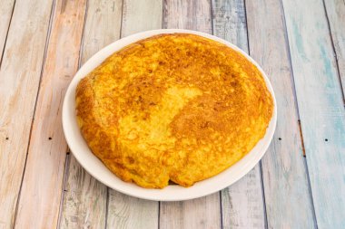 İspanyol omleti beyaz tabakta hafif ahşap masaları olan bir İspanyol restoranında pişiriliyor.