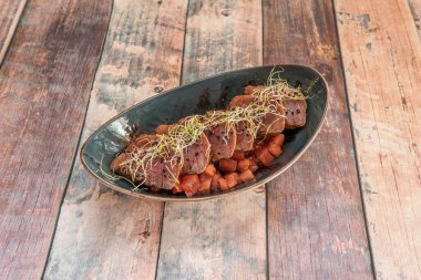 Ahşap bir masada, koyu bir kasede doğranmış domates ve fasulye filizli kırmızı ton balığı tarifi.