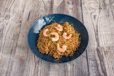 Sebzeli sahanda şehriye ve mavi tabakta yakisoba soslu karides.