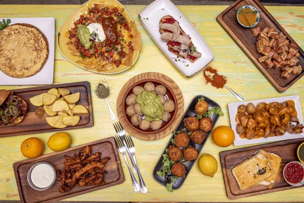 メキシコ料理のタッチで主にスペイン料理の料理のセットのイメージ モジョ パタータ ブラバス ナチョス グアカモーレ ポテトオムレツ ベリーサラダ — ストック写真