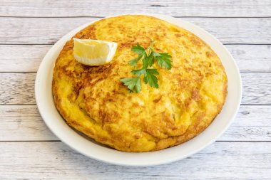 Maydanozlu İspanyol patates omleti ve İspanyol restoranında garnitür olarak servis edilen limon.