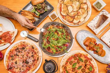 İspanyol yemeği tabakları ve üstünde kömür un hamurlu pizza ve çatal oymaya hazır bir adam eli olan İtalyan pizzaları.