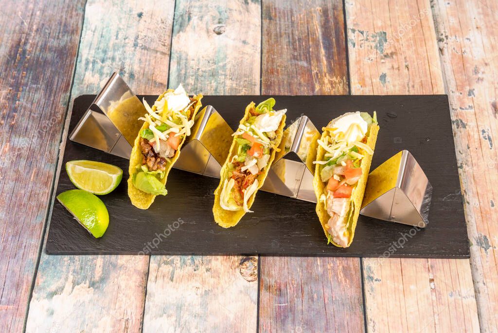 Tacos de harina de maíz crujiente de variados sabores sobre soporte