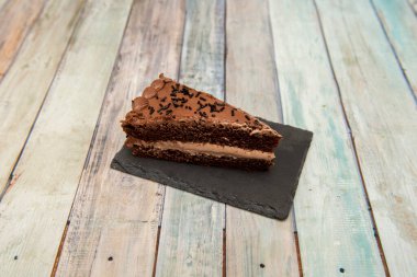 Bir porsiyon koyu çikolatalı kek, iki katlı sünger keki ve siyah bir tabağı doldurmak..