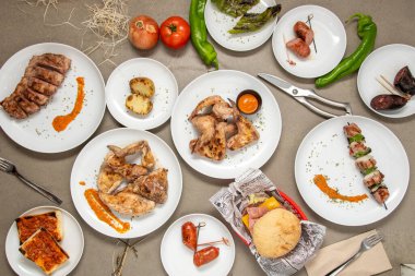 Tabaklar gri bir masada kömür ızgarasında ızgara. Kızarmış patates, kızarmış sucuk, tavuk şişi, domuz kaburgası, sığır burger..