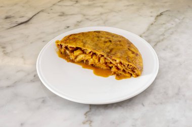 Yarım sulu patates omleti, soğanlı, beyaz tabakta et ve mermer masa.