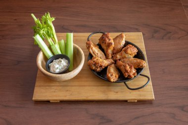 Siyah tavada tavuk kanadı, kereviz ve bambu çubuğunda Gorgonzola peyniri sosu..