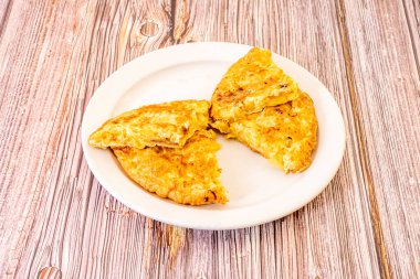 Kelebek omleti. Beyaz tabakta yumurtalı İspanyol omleti ve kırmızı ahşap masa.