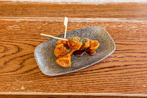 Crispy chicken breast skewers on a gray plate and with teriyaki sauce