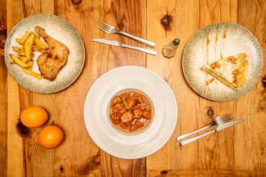 Et yahnili menü, kızarmış tavuk budu ve lüks patates, cevizli kremalı turta. Çam ağacından bir masa üzerinde çatal ve bıçaklar