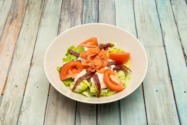 熏制沙拉 配上挪威鲑鱼 桑多纳的凤尾鱼 切碎的西红柿和白碗上的冰生菜 — 图库照片