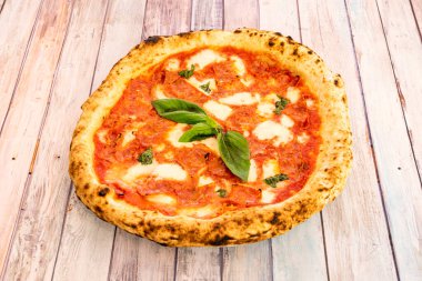 Üzerinde çok baharatlı sucuk ve fesleğen olan süper ince un hamurlu küçük pizza..