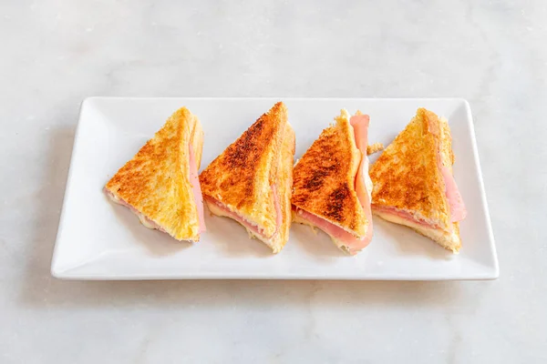 白皿の上にチーズとハムのグリルしたスライスパンの混合サンドイッチ — ストック写真