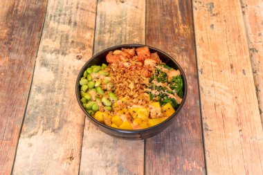 Norveç somonu, çıtır soğan, Japon edamaması, Afrika mangosu ve yosun salatasıyla siyah bir kase Hawaii dürümü..