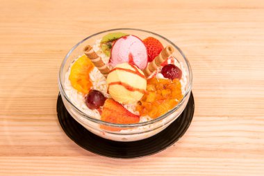 Fruit salad and ice cream with cheese, red grapes, ripe strawberries, kiwi and biscuit wafers.