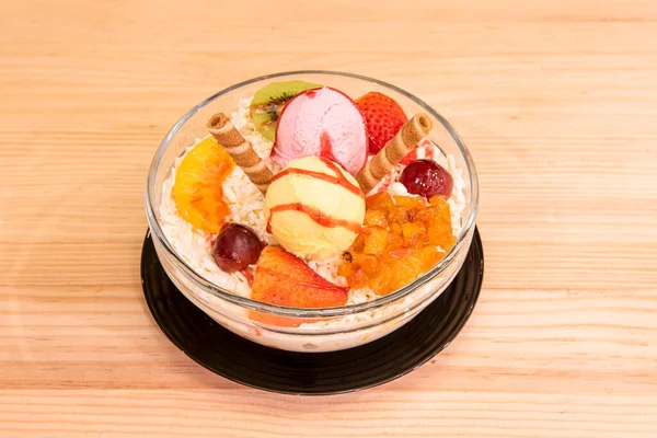 Fruit salad and ice cream with cheese, red grapes, ripe strawberries, kiwi and biscuit wafers.