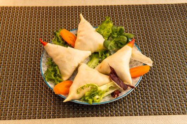 Pakistan restoranında Hint sebzeli samosa, marul ve havuç garnitürlü servis ediliyor.