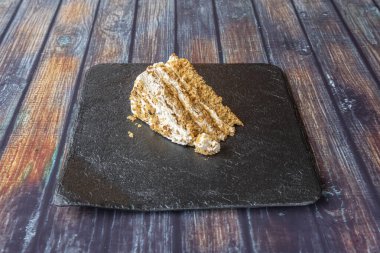 Kare tabakta üç dolgulu ve üstünde fındık olan havuçlu kek porsiyonu.