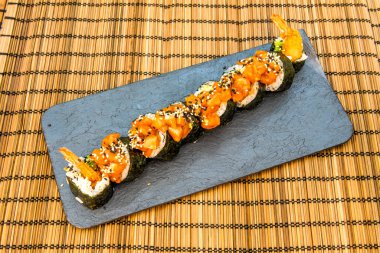 Pirinç ve karidesli yosun ve siyah tabakta susam tohumu.