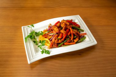 Sebzeli karamelize biftek şeritleri, marul filizleri ve Çinli bir aşçı tarafından pişirilen yenilebilir çiçekler.