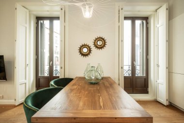 Zeminden tavana yemek masası üzerinde cam vazolar ve klasik tarzda dekore edilmiş kiralık bir apartman dairesi.