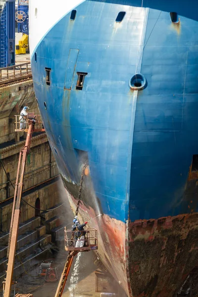 不純物を洗浄し ジブラルタルの造船所の商船の船体から圧力サンドブラストで塗料を除去する労働者 — ストック写真