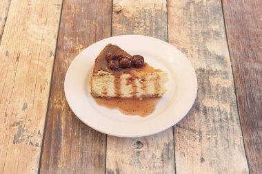 Beyaz tabak ve ahşap masada kırmızı böğürtlen reçelli cheesecake ve çilek porsiyonu