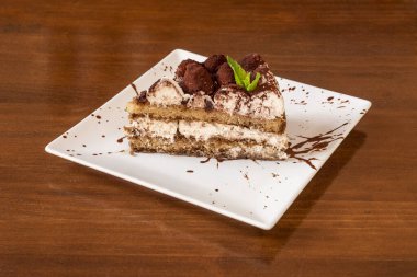 İtalyan tiramisu kekinin üstünde çikolata mantarı, çikolata şurubu ve beyaz bir tabakta bolca krema olan harika ve kışkırtıcı kısmı.