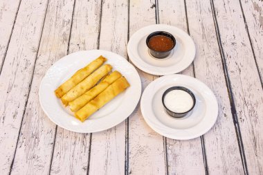 Bir tabak yağda kızartılmış peynirli flüt ve iki kutu siyah sos.