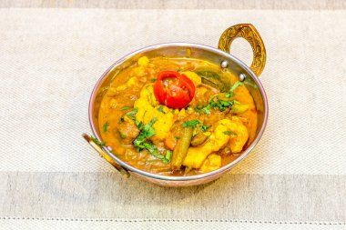 Indian curry of stewed vegetables, tomatoes, carrots, cauliflower, flat green beans with chopped fresh parsley