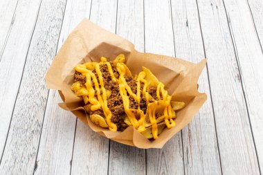 French fries appetizer with minced beef stew and lots of cheddar cheese cream on brown food paper