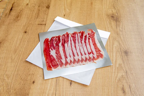 Köy ekmeğiyle harika bir sandviç yapmak için gümüş folyo üzerinde leziz İber jambonu dilimleri.