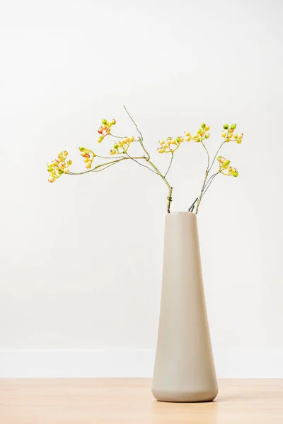 木製の床と白の背景に未熟な装飾的なブルーベリーの枝と長い灰色の花瓶 — ストック写真