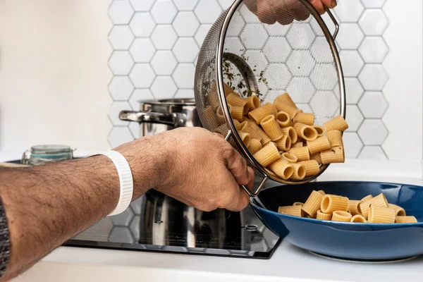 Férfi Kezei Főtt Tésztát Öntenek Oregánóval Egy Kék Tányérba Konyhapult — Stock Fotó