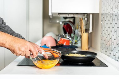 Adamın elleri İspanyol omleti pişirmek için yumurta çırpıyor.