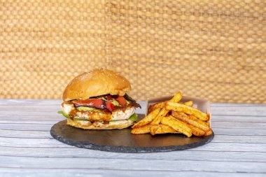 Bol barbekü soslu tavuk burger, kavrulmuş kırmızı biber, guacamole ve yanında paprika kızartması.