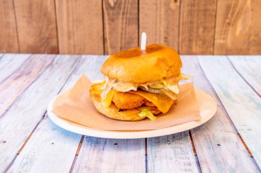 Eritilmiş çedar peyniri, beyaz soğan ve hardal soslu basit tavuk burgeri.