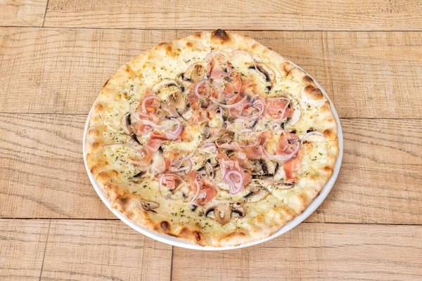 Great family pizza sliced and cooked with carbonara recipe with red onion, ham, mushrooms and melted cheese