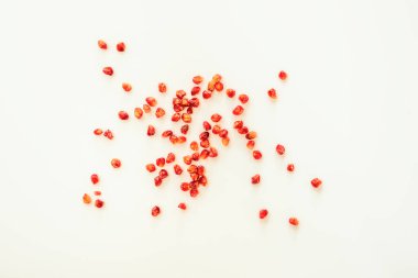 Beyaz bir yüzeyde üstten görünen gevşek nar taneleri