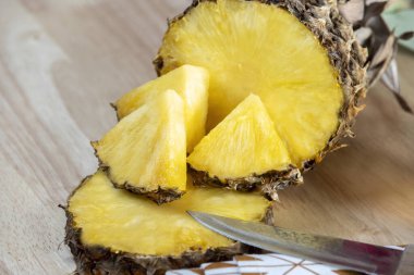 Ananas parçaları ve bıçakla ikiye bölünmüş bir ananas.