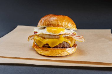 Yağda yumurta, dilimlenmiş domuz pastırması, erimiş çedar peyniri, dilimlenmiş beyaz soğan ve kahverengi yağsız kâğıt.